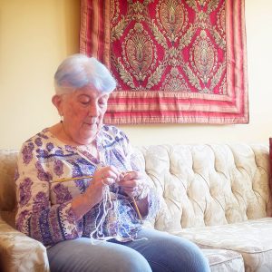 Person knitting on the couch at their SCOC resident